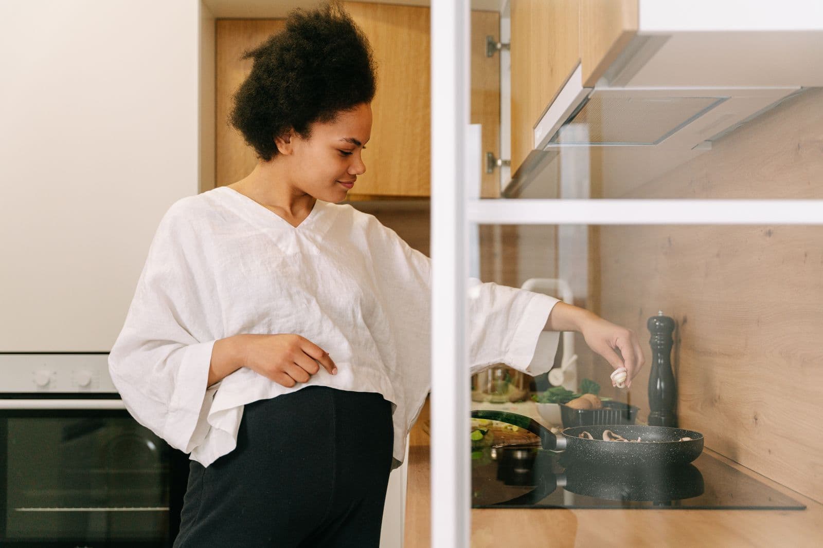 Person preparing a meal on the stovetop in a bright home kitchen