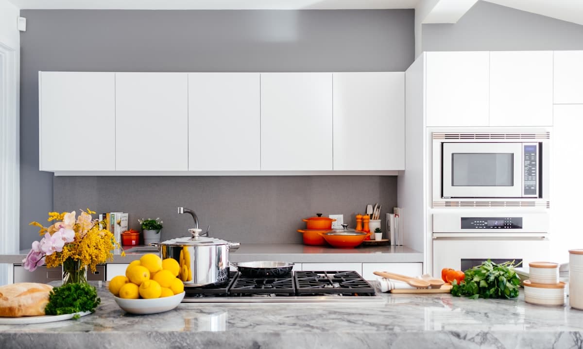Clean modern kitchen with marble counters, fresh produce, and organized cabinets